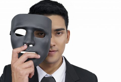 black mask with a young businessman wearing a suit, concept, spying or ambiguous